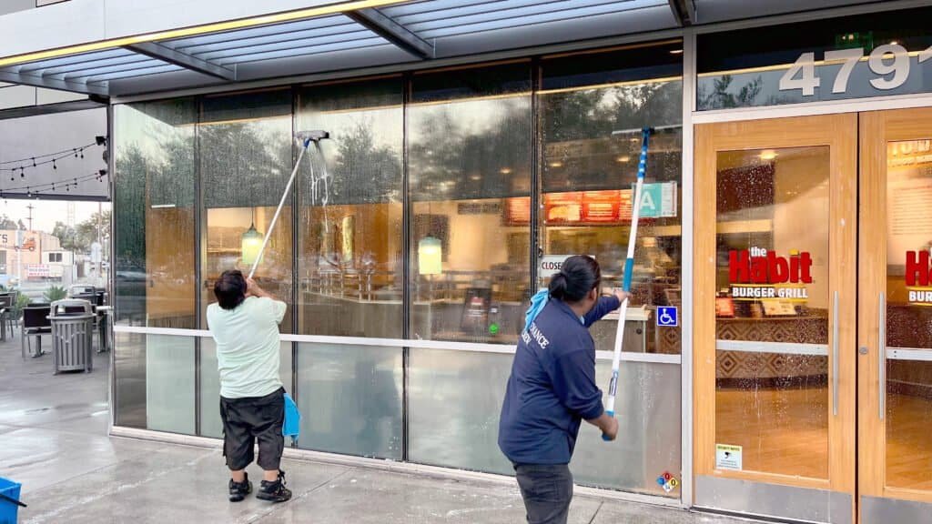 High-pressure cleaning of storefront glass windows in California.