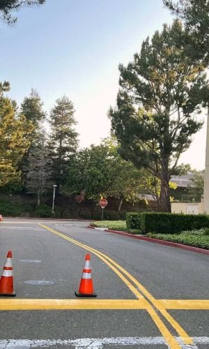 Pressure washing driveway with traffic cones in California.
