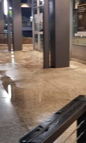 Pressure washing sidewalk and storefront in California.