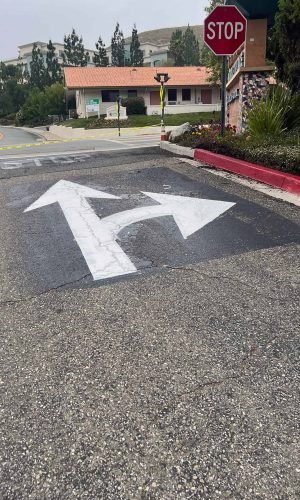 Freshly painted directional arrows and stop sign at intersection in California.