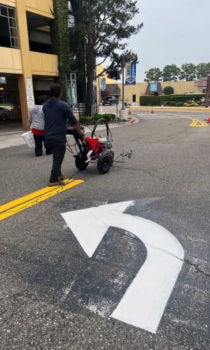 Professional pressure washing equipment cleaning city street pavement and arrow markings.
