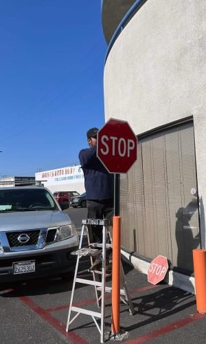 Worker installing stop sign for safety during pressure washing service.