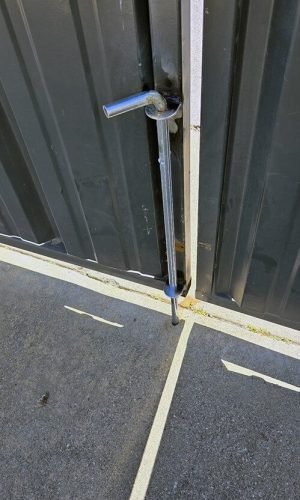 Close-up of pressure washing tool against a metal gate for cleaning and maintenance.