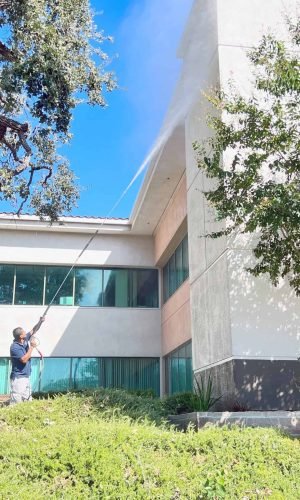 Pressure washing building facade for cleaning and maintenance.