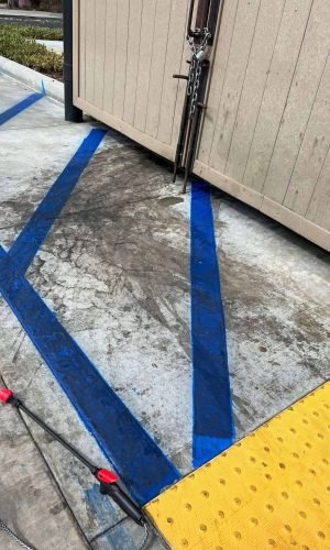 Cleaned blue parking lot lines with pressure washer on concrete surface.
