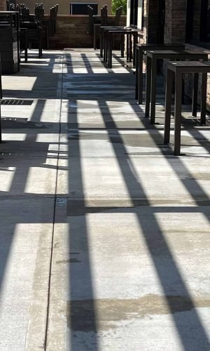 Clean concrete patio with shadows cast by outdoor furniture and railing in California.