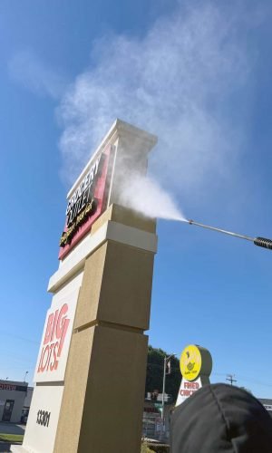 Power washing a large outdoor sign for California Pressure Washing with high-pressure water.