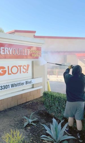 Professional pressure washing of storefront exterior at California shopping center in California.