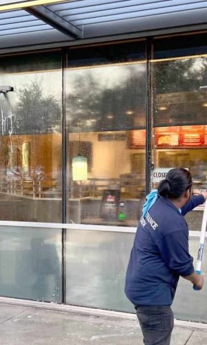 High-pressure cleaning of storefront glass windows in California.