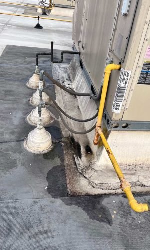 Commercial HVAC unit on roof with visible pipes and cleaning area in California.