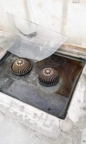 Commercial drain cover being pressure washed to remove grime and buildup.