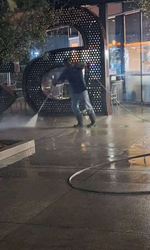 Professional pressure washing cleaning outdoor concrete surface at night in California.