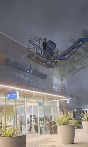 Professional pressure washing of commercial storefront exterior at night in California.