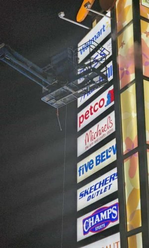 Commercial shopping center signage with retail store logos at night.