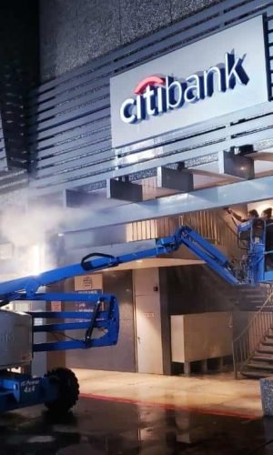 Pressure washing commercial building exterior with a boom lift.