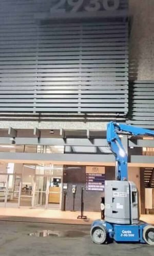 Commercial building pressure washing with industrial equipment in progress.